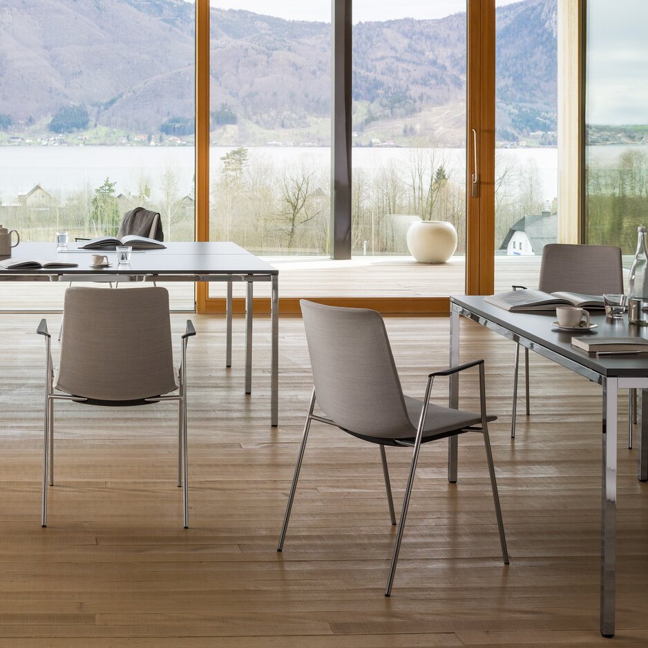 Table with chairs in a glazed room with wooden floor. 