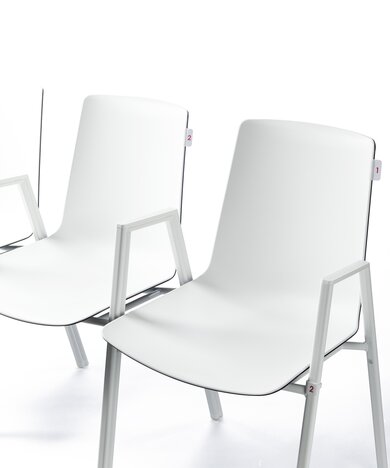 witte aan elkaar gekoppelde stoelen met stoelnummering en rijnummering