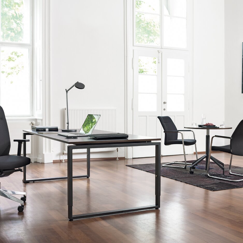 Office with a desk, a black swivel chair and two cantilever chairs.