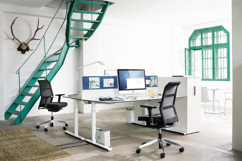 Office with two desks, black swivel chairs and a white cabinet. 