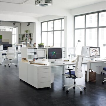 White swivel chairs with white office desks in a modern office.