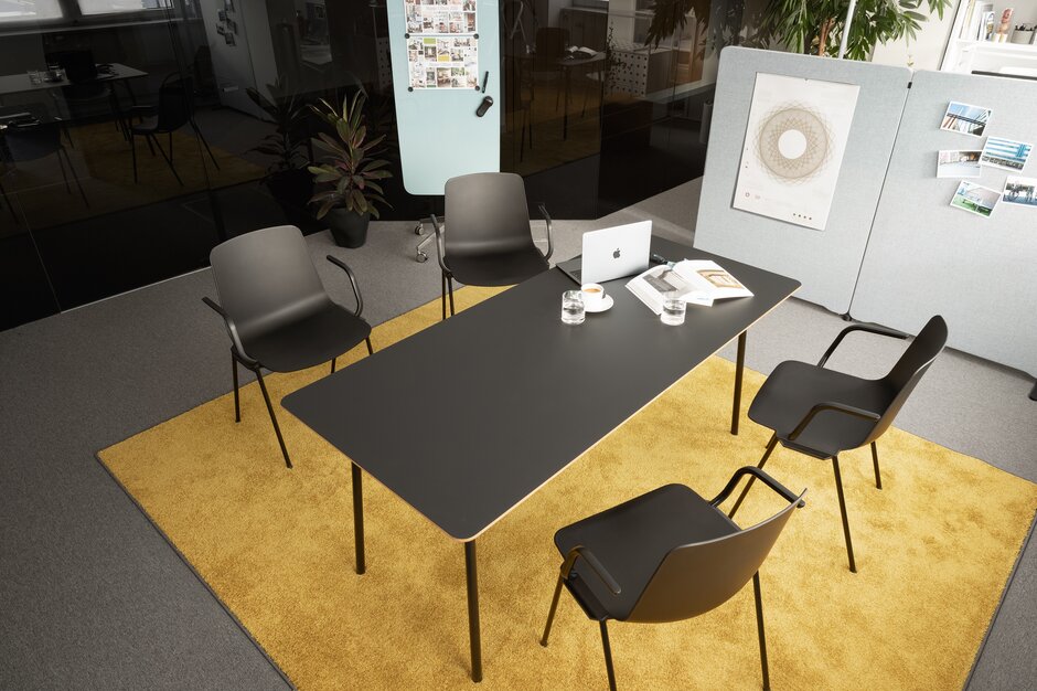 Four black stacking chairs at a black table.
