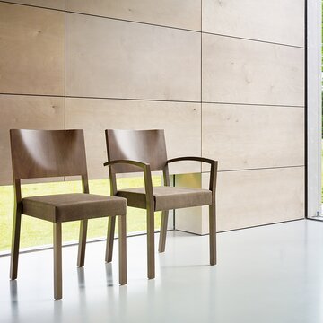 une chaise en bois avec accoudoirs et une chaise en bois sans accoudoirs devant un mur carrelé