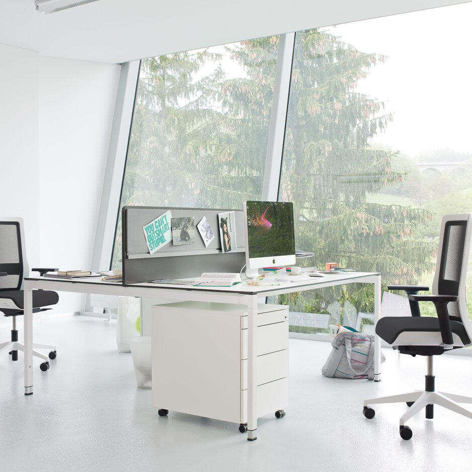 Light office with a white desk and black/white swivel chairs.