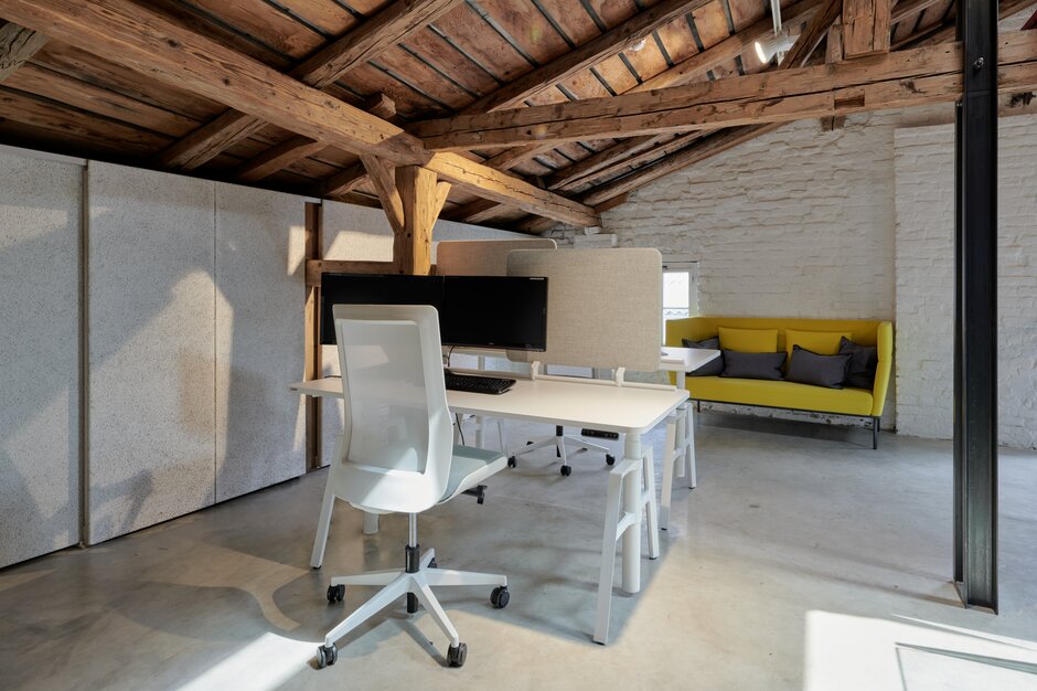 White office desk with white swivel chair and a yellow couch. | © raumpixel.at