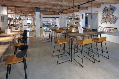 Cafébereich mit Bistrotischen, Stühlen, Barhockern und Stehtischen.