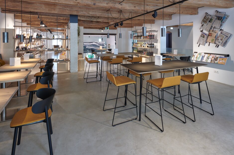 Cafébereich mit Bistrotischen, Stühlen, Barhockern und Stehtischen.