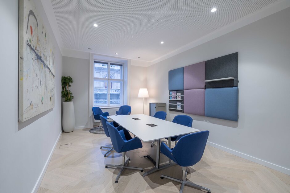 Meetingraum mit blauen Stühlen und einem weißen Konferenztisch. | © Martin Zorn Photography