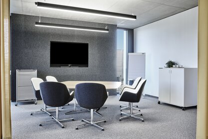 Meeting room with conference furniture and screen.