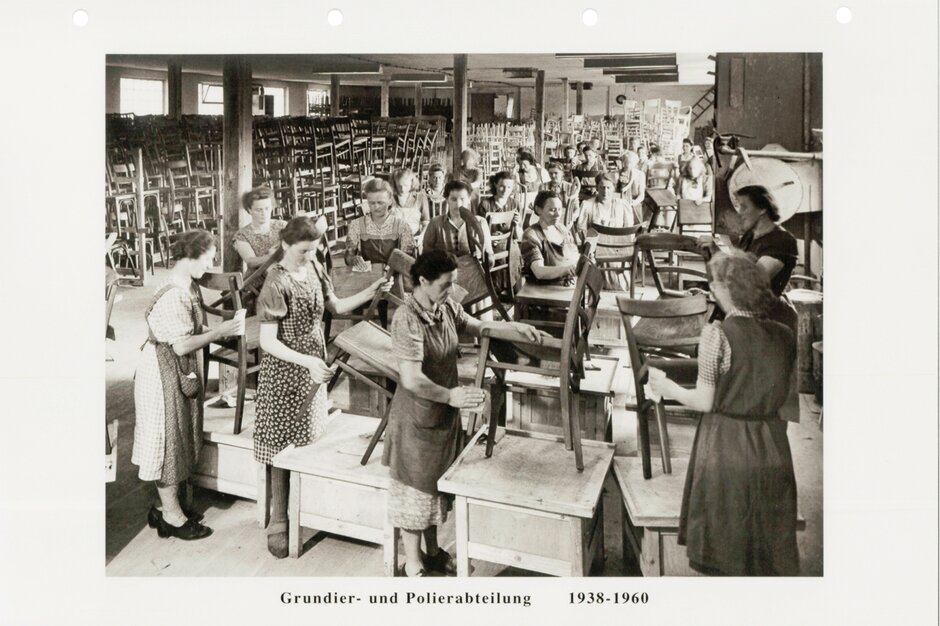 Photographie en noir et blanc de personnes travaillant dans une salle de production de chaises