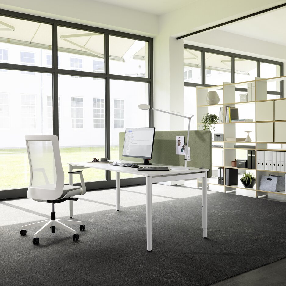Weißer Schreibtisch mit weißem Drehstuhl in einem hellen Büroraum.