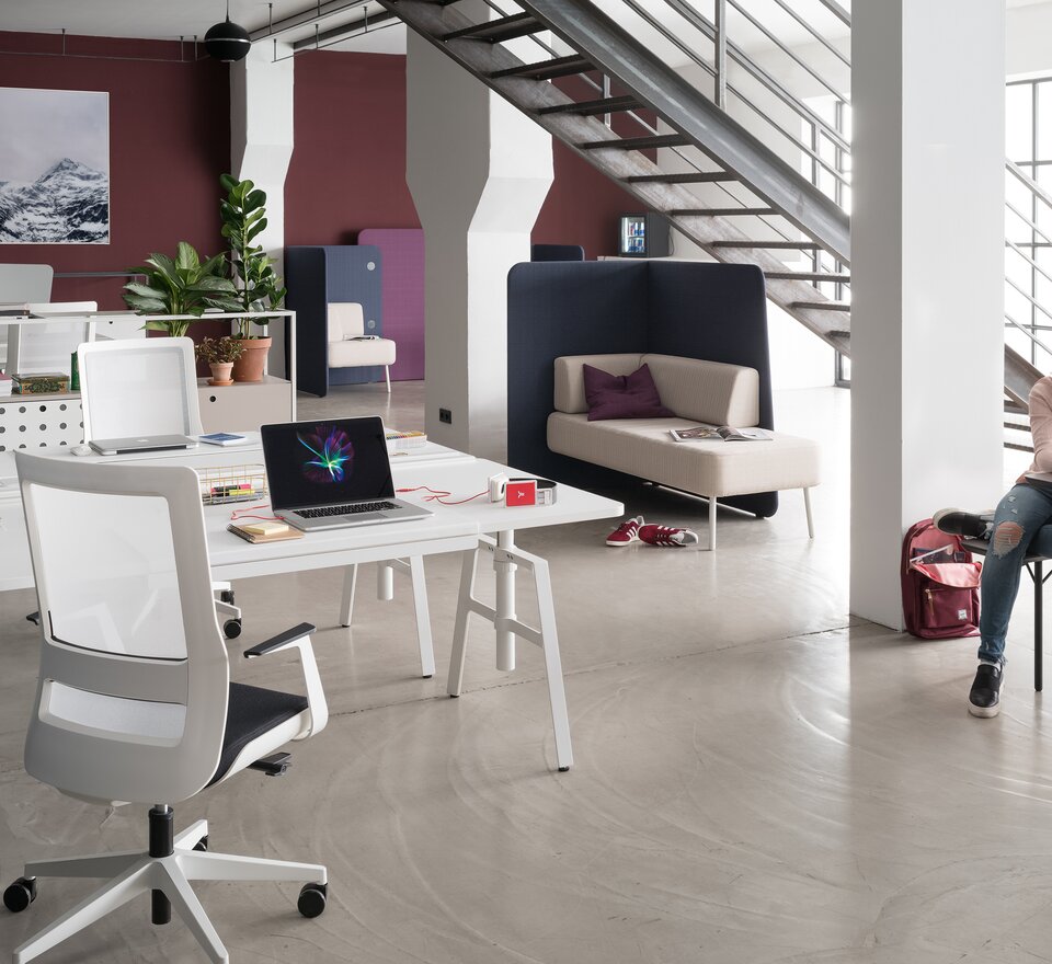 Teambüro mit weißen Möbeln und einer roten Wand.