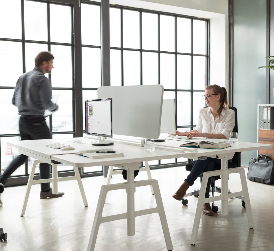 Two people are sitting on an white office desk.