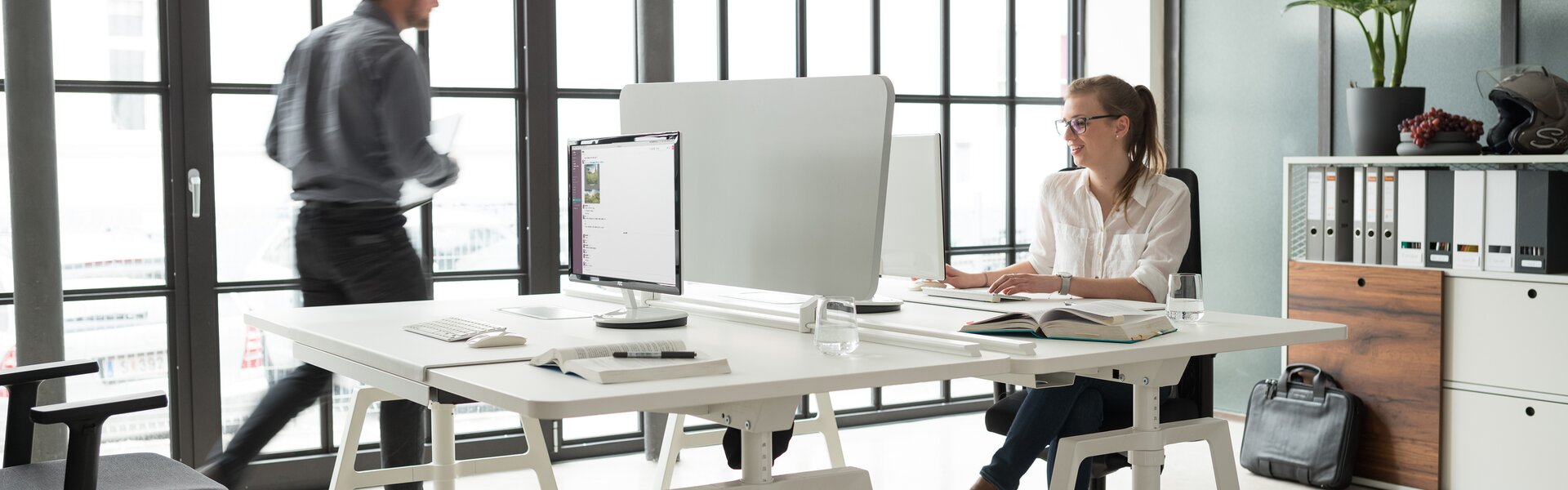 Two people are sitting on an white office desk.