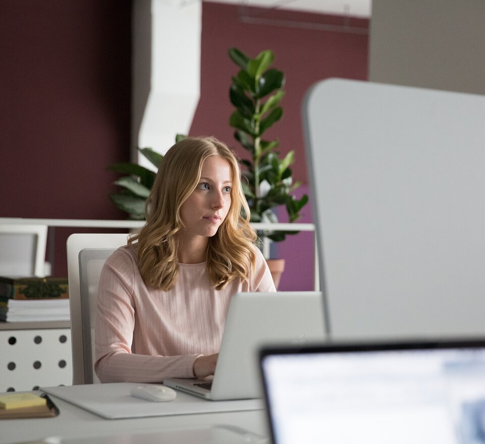 A person sitting on an office desk in front of a notebook.