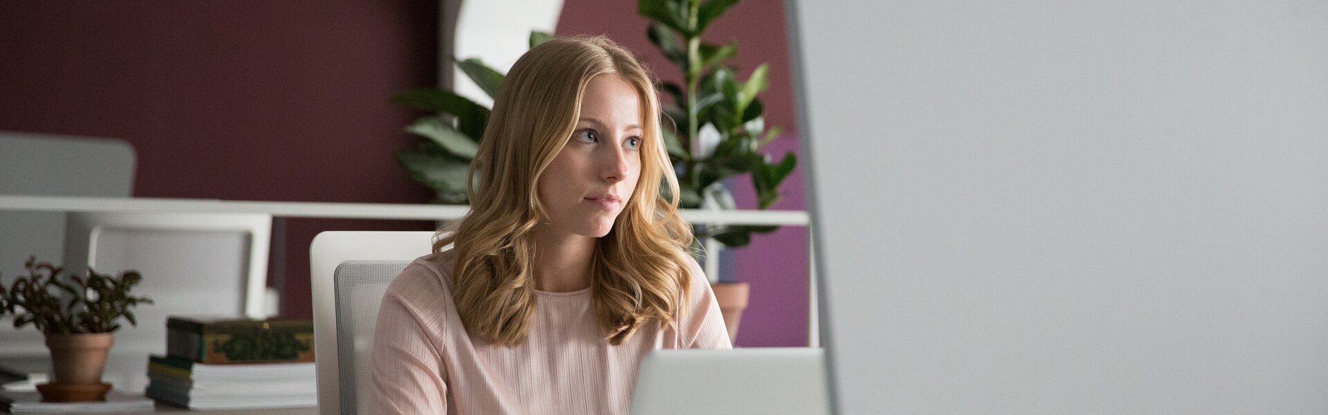 A person sitting on an office desk in front of a notebook.