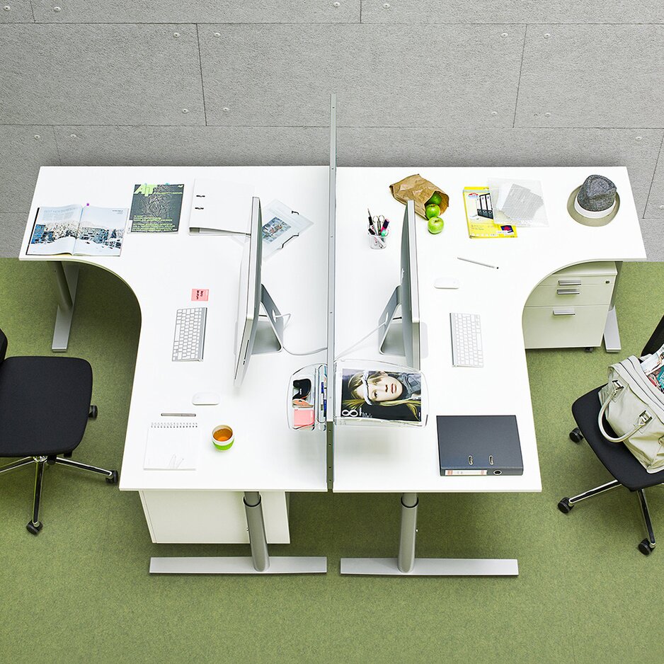 Two office desks in a green room, photographed from above.