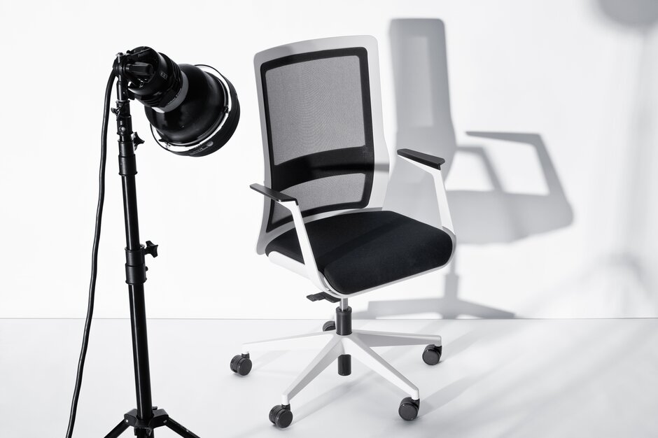 poi swivel chair White swivel chair with black mesh back and armrest behind a microphone.