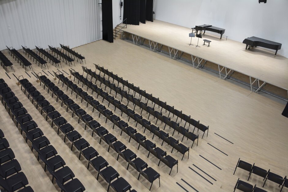 auditorium avec chaises noires et une estrade avec un piano dessus