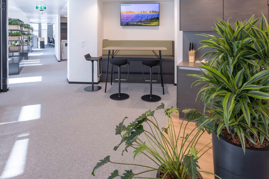 Clean Capital Energy | © Martin Zorn Photography Hoge tafel met bank en krukken, kitchette en planten | © Martin Zorn Photography
