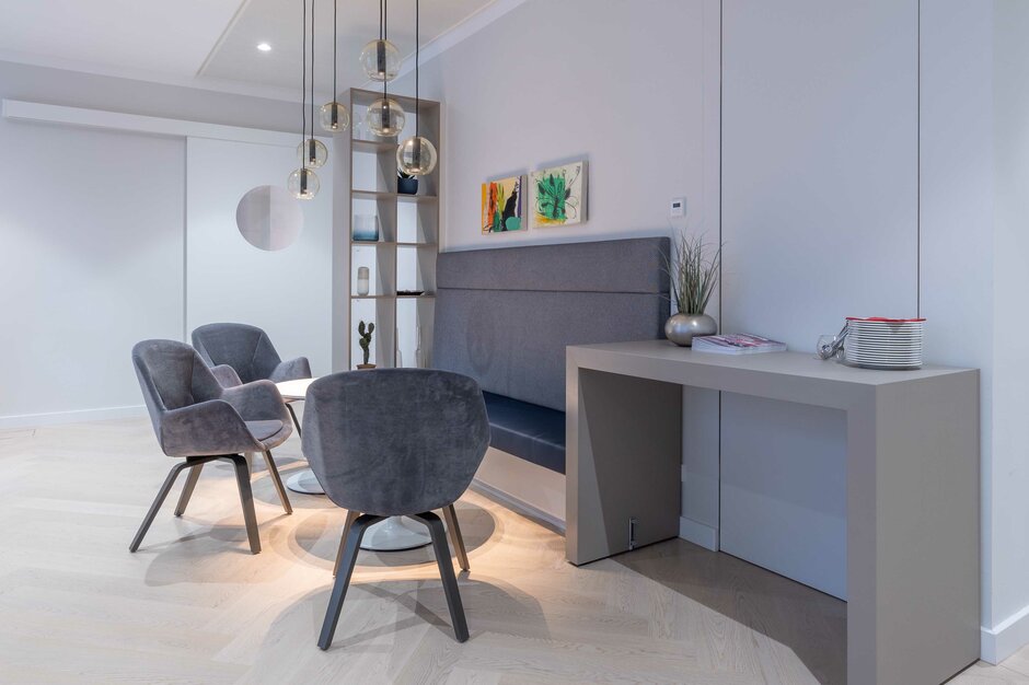 Espace lounge avec chaises grises et lampes suspendues. | © Martin Zorn Photography