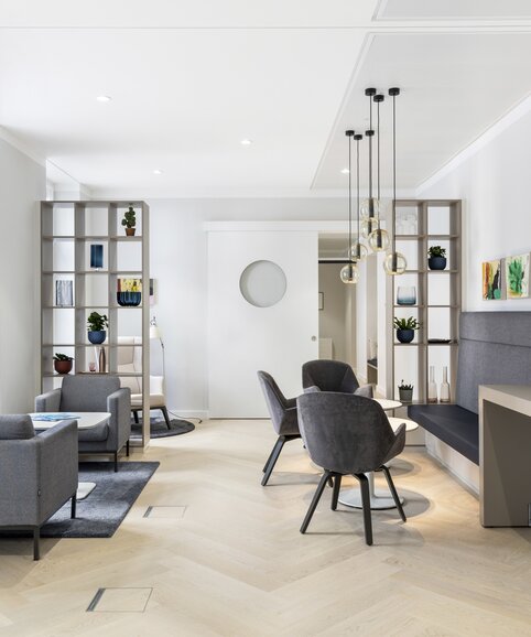 Espace lounge avec chaises grises et lampes suspendues. | © PicMyPlace