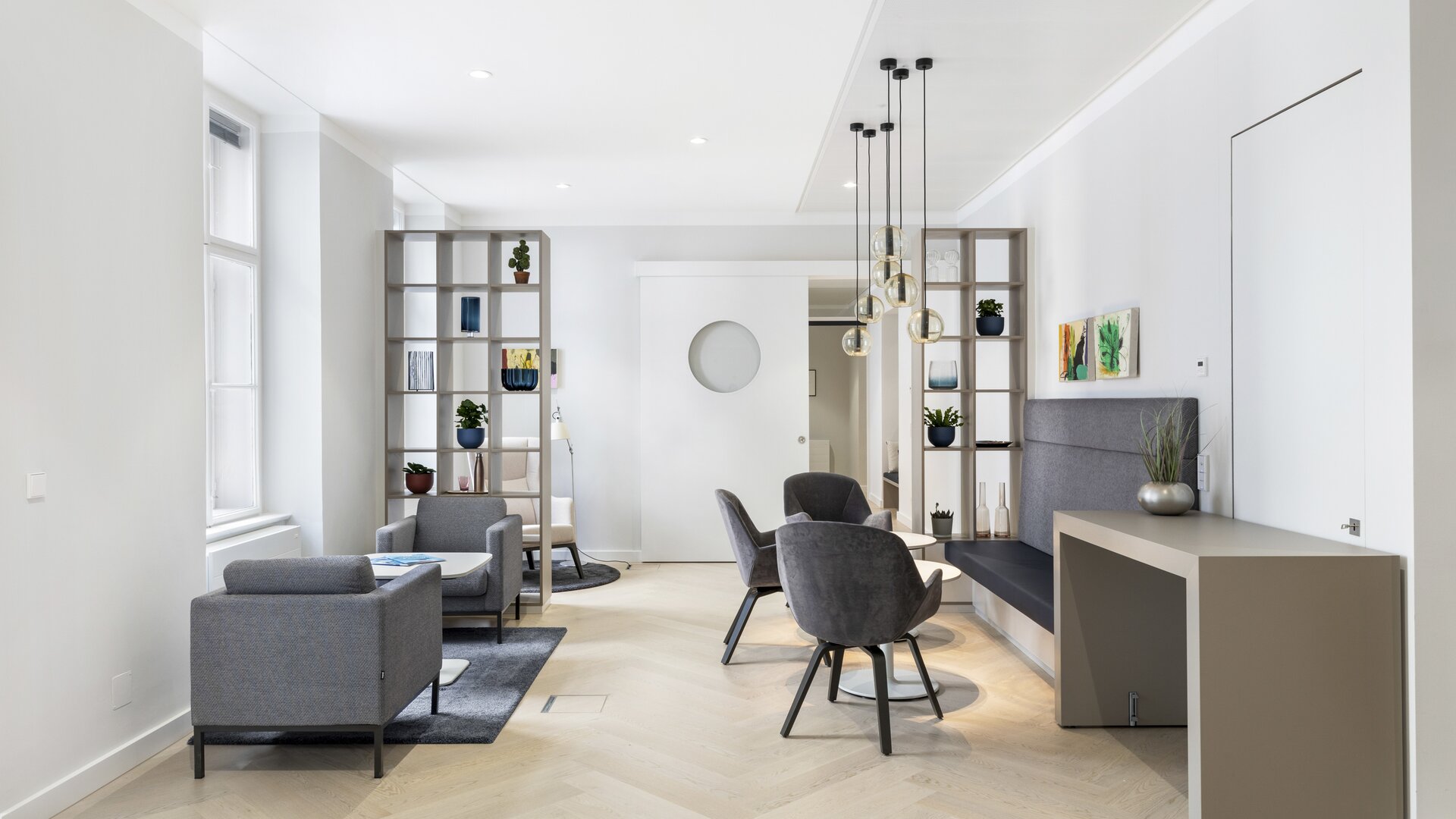 Espace lounge avec chaises grises et lampes suspendues. | © PicMyPlace