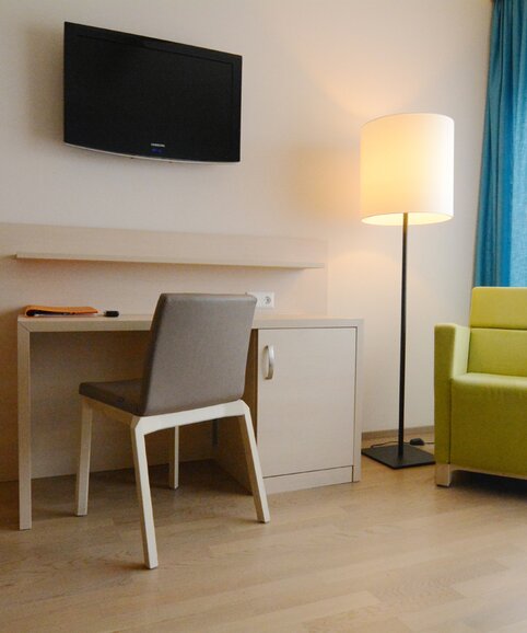 SeneCura chaise en bois et fauteuil vert devant un écran