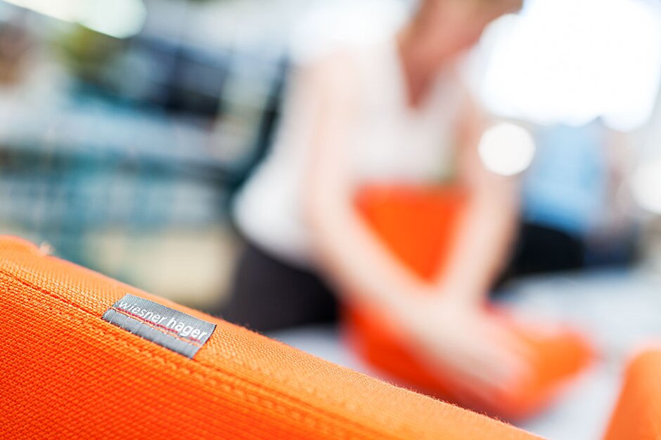 Polsterei Wiesner-Hager Detailaufnahme eines orangen gepolsterten Stuhles.