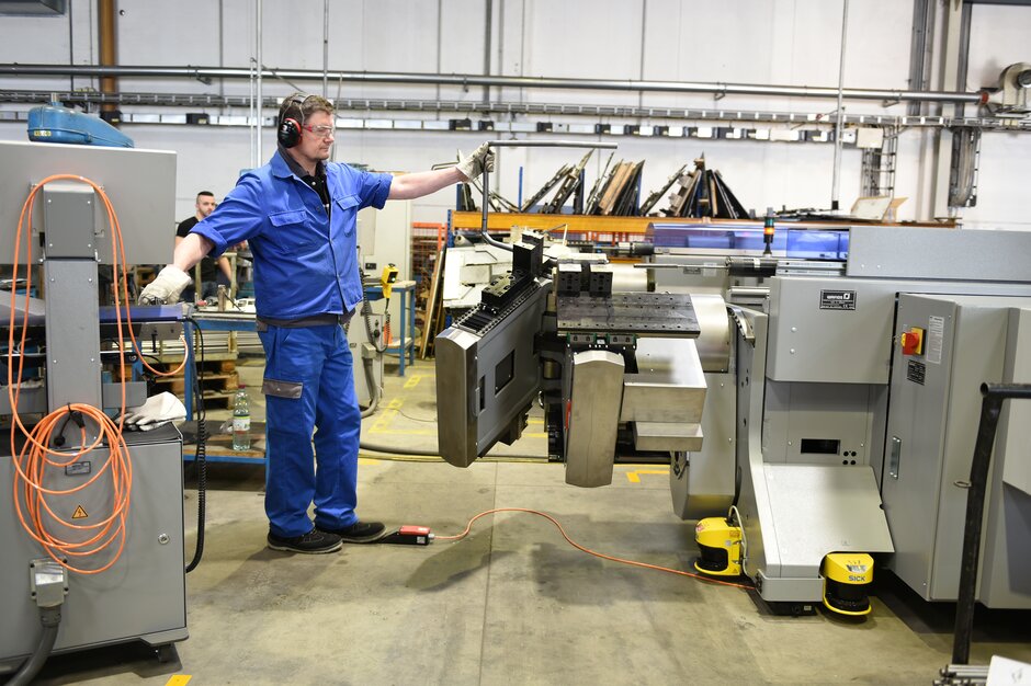 Metallfertigung Person in blauer Arbeitskleidung bedient eine Maschine.