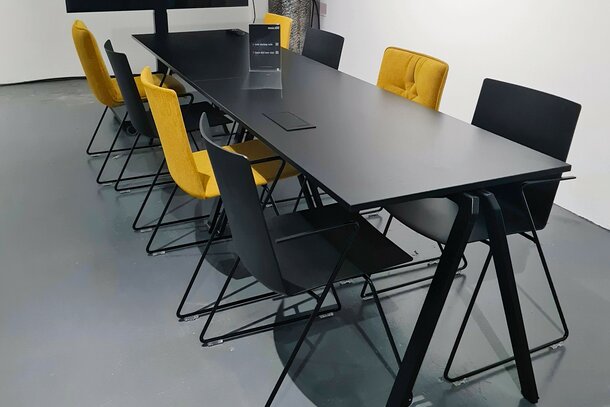 Schwarzer Tisch mit schwarzen und gelben Kufenstühlen. 