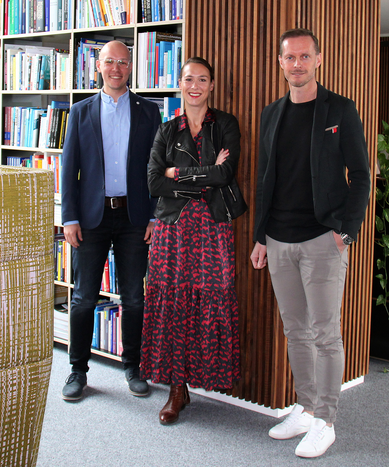 Drei Personen stehen vor einem Bücherregal.  | © plenos
