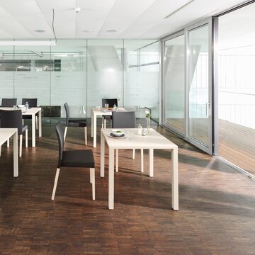 White tables in a canteen with a wooden floor.