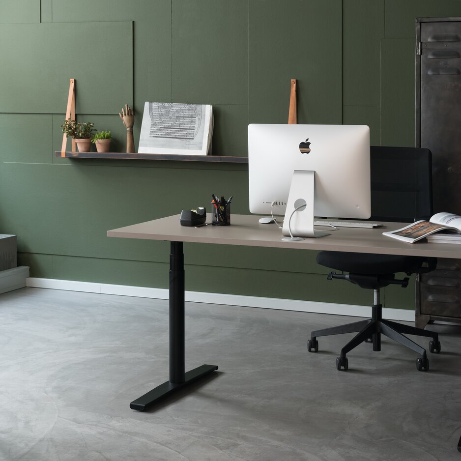 Höhenverstellbarer Schreibtisch in einem Büro mit grüner Wand.