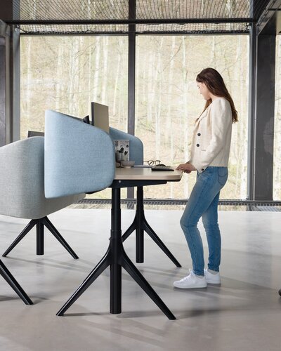 Frau an elektrisch höhenverstellbarem Schreibtisch