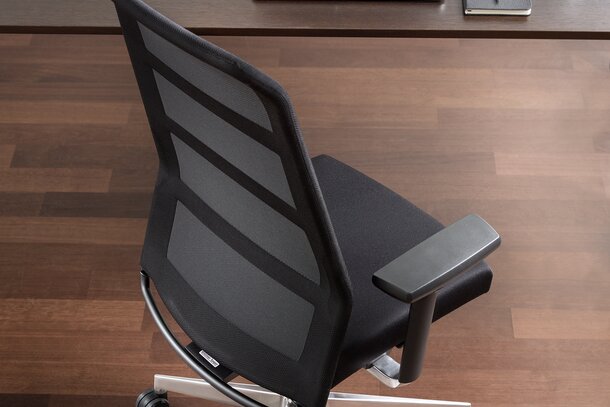 Black swivel chair at a desk, photographed from above.