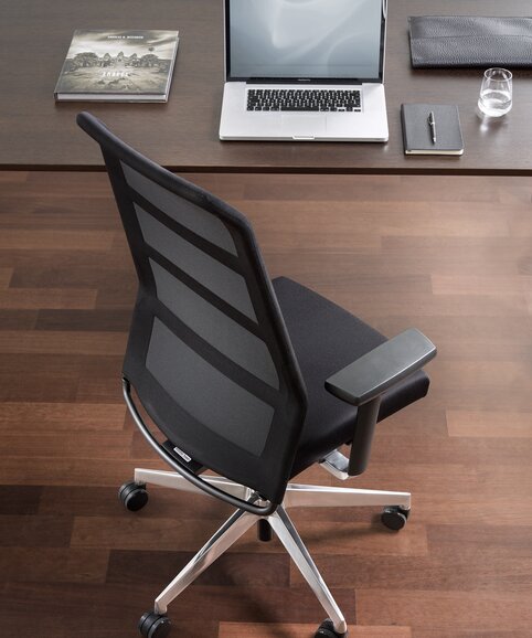 Black swivel chair at a desk, photographed from above.