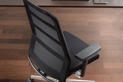 Black swivel chair at a desk, photographed from above.