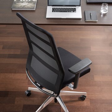 Black swivel chair at a desk, photographed from above.