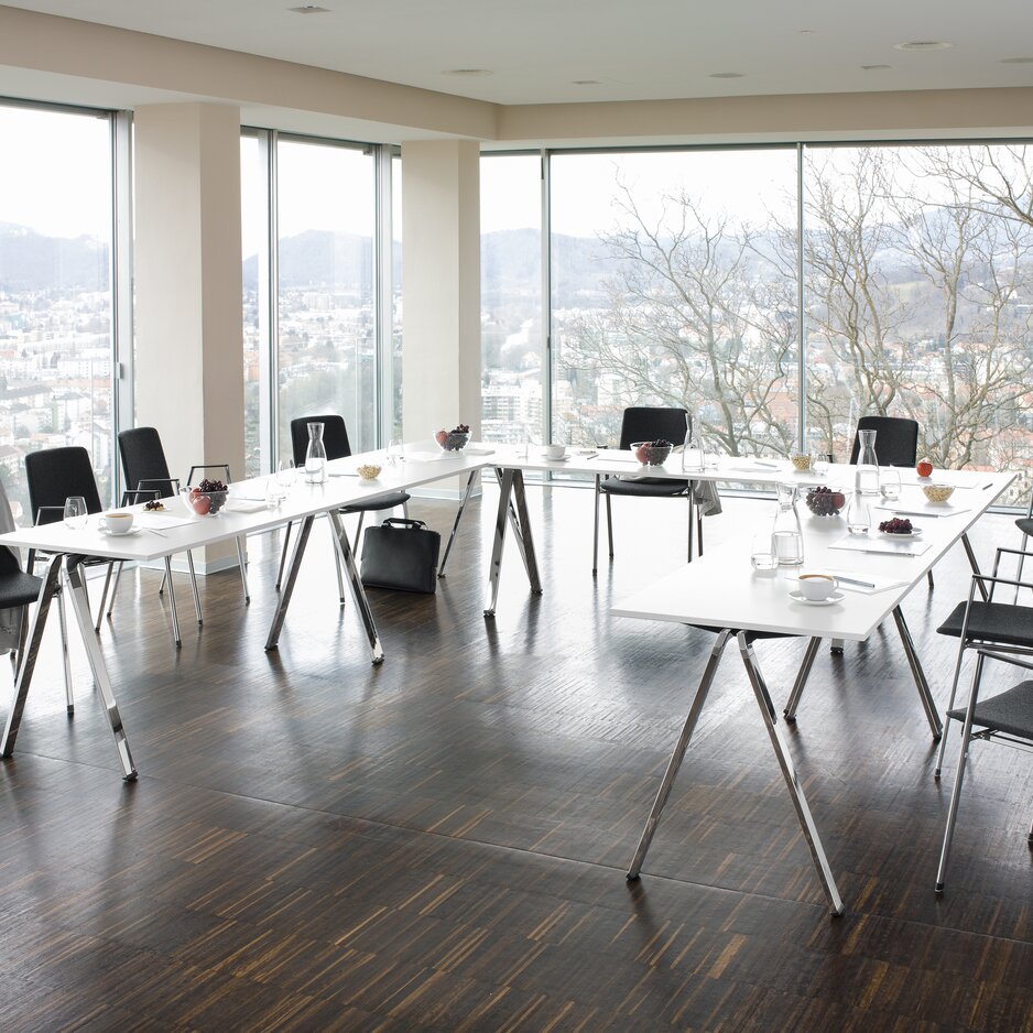 Meetingroom with white stacking tables and dark chairs.