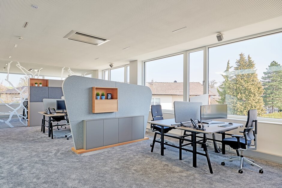 Office with desks, black swivel chairs and a gray floor.