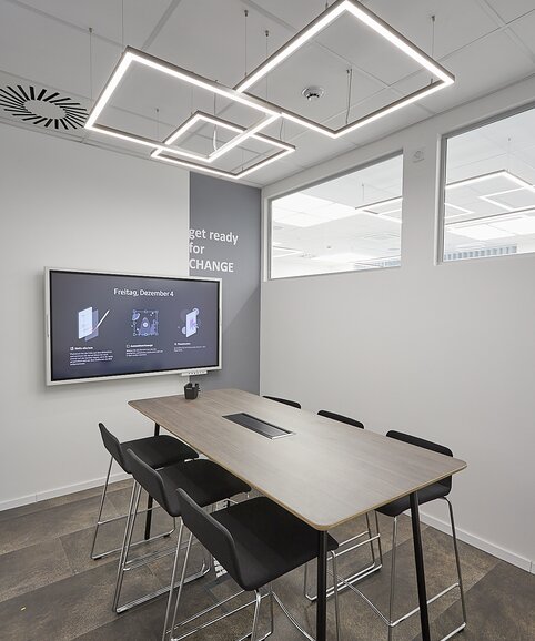 Meeting room with black barstools and a high table.