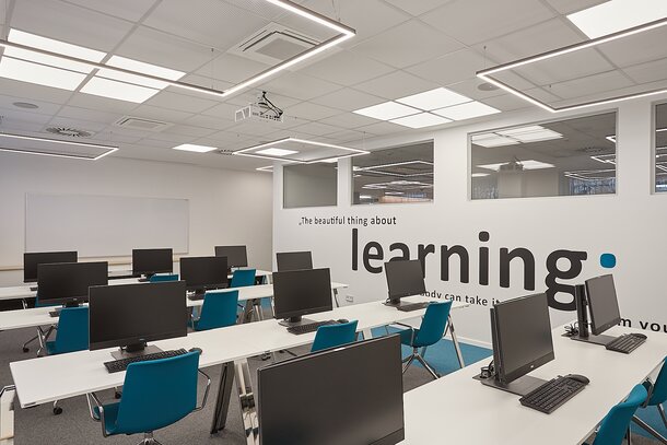 AHT Training room with computer workplaces and blue conference chairs.