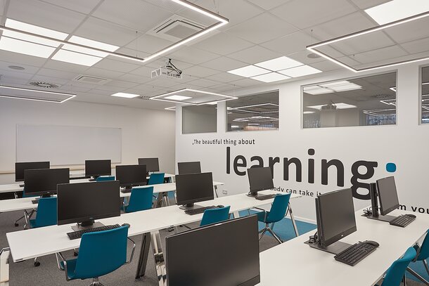 Training room with computer workplaces and blue conference chairs.