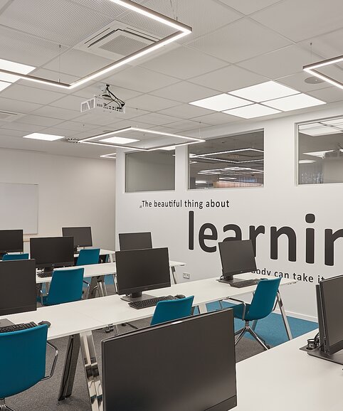 AHT Training room with computer workplaces and blue conference chairs.