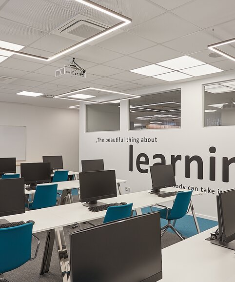 Training room with computer workplaces and blue conference chairs.