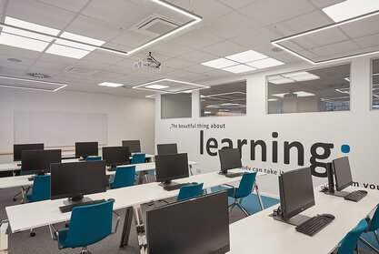 AHT Training room with computer workplaces and blue conference chairs.