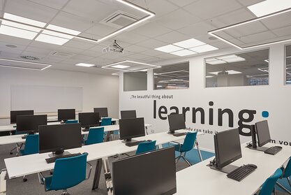 Training room with computer workplaces and blue conference chairs.