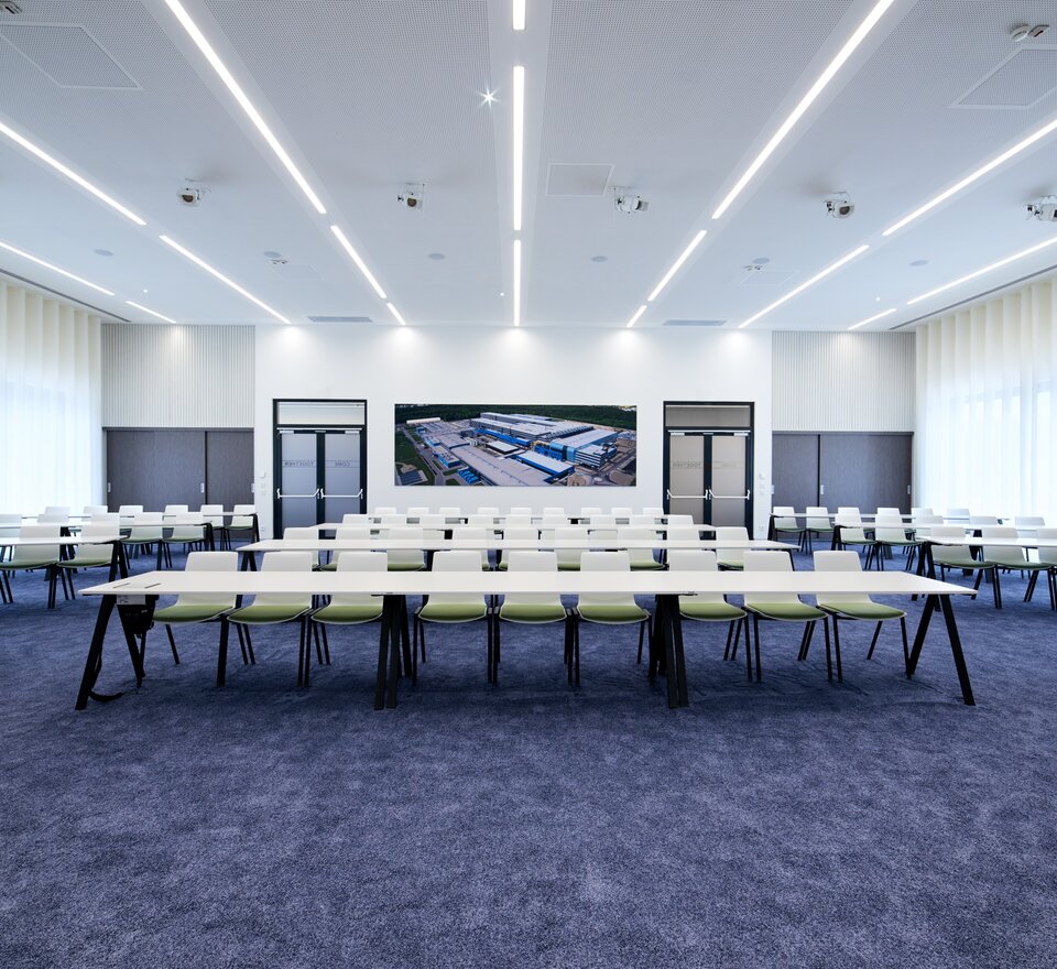 Seminar room with white tables and geen chairs.