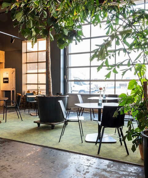 Café with black bistro tables and black chairs. | © BLINK Fotografie